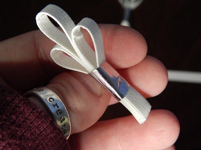 I hand ripped strips of ¼” white Pro® Gaff tape. I married 2 pieces together. Then I took 3 married strips, bent them each over individually, creating a loop and combined them together like a tiny bouquet, then I secured them together by wrapping a piece of silver Pro® Sheen around the stem of the “bouquet”. I hand ripped strips of ¼” white Pro® Gaff tape. I married 2 pieces together. Then I took 3 married strips, bent them each over individually, creating a loop and combined them together like a tiny bouquet, then I secured them together by wrapping a piece of silver Pro® Sheen around the stem of the “bouquet”.